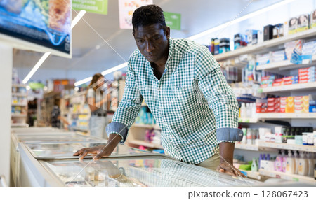 Man choosing frozen food in supermarket Man choosing frozen food in supermarket 128067423