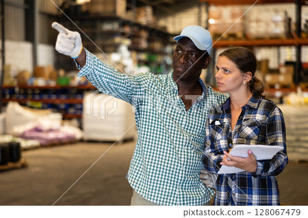 Woman and man discussing work details in storehouse Woman and man discussing work details in storehouse 128067479