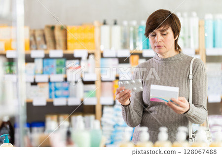 Woman in winter clothes looking for medicine in pharmacy Woman in winter clothes looking for medicine in pharmacy 128067488