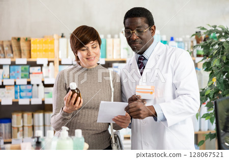 Woman choose buy antitussive syrup at pharmacy. African man in background 128067521