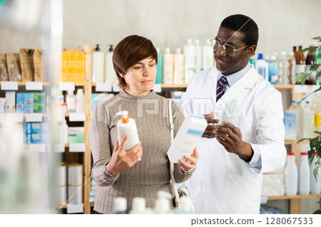 Woman choosing cream with help from pharmacist 128067533