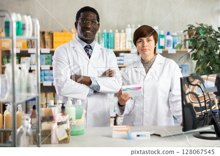 Woman pharmacist and African man assistant is waiting for client in drugstore 128067545