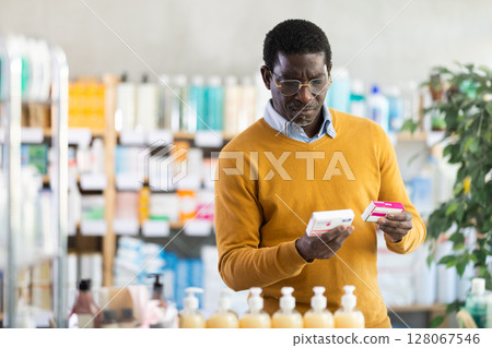 Male buyer in glasses buys paracetamol medicine at pharmacy 128067546