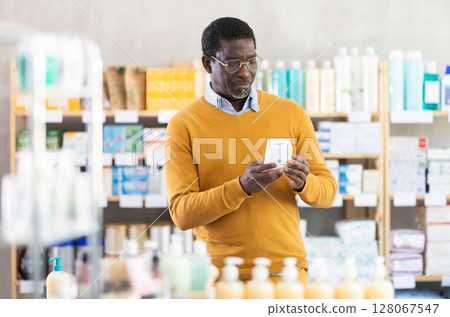 African man buyer select cream in drug store 128067547