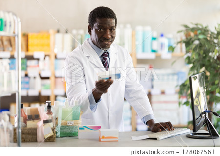 Pharmacist checking medication details before offering to customer in drugstore 128067561