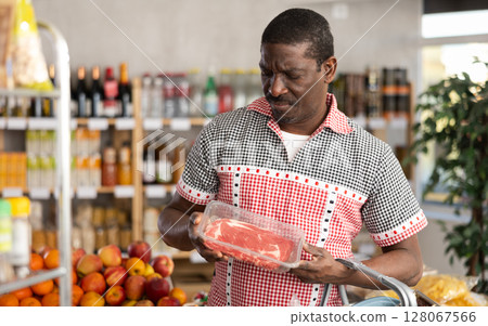 African man choose raw beef entrecote meat for roasting in store African man choose raw beef entrecote meat for roasting in store 128067566