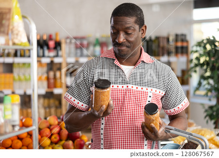 African man make choice choose consider canned pickled lentil in store African man make choice choose consider canned pickled lentil in store 128067567