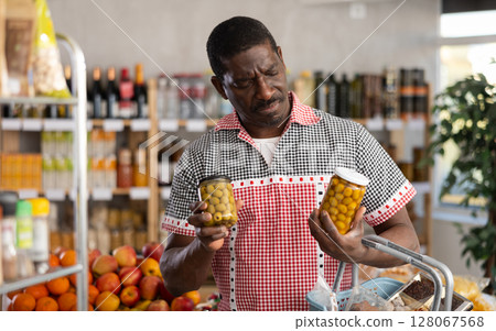 Adult man choosing olives in grocery store Adult man choosing olives in grocery store 128067568