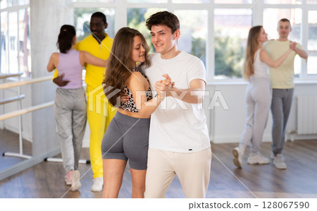 Young man and woman practicing waltz dance in pair in training hall Young man and woman practicing waltz dance in pair in training hall 128067590