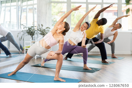 Girl doing Extended Side Angle Pose at yoga training Girl doing Extended Side Angle Pose at yoga training 128067650