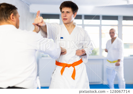 Concentrated guy honing punching techniques during kumite at karate training 128067714