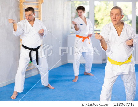 Mature man with other athletes of different ages during karate or judo classes Mature man with other athletes of different ages during karate or judo classes 128067715