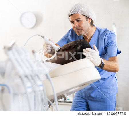 Professional aesthetician administering high frequency ultrasound facial procedure on man Professional aesthetician administering high frequency ultrasound facial procedure on man 128067718