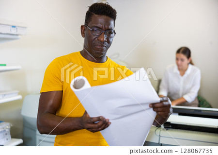 Middle-aged African American man holding large format paper whatman in a roll in the middle of the typography Middle-aged African American man holding large format paper whatman in a roll in the middle of the typography 128067735