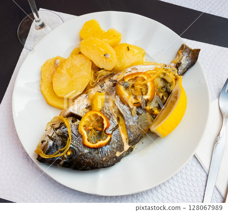 There is large piece of baked fish dorado and potato garnish There is large piece of baked fish dorado and potato garnish 128067989