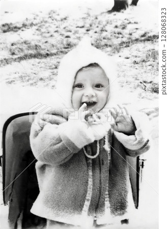 Vintage portrait of a cute little boy in a white cap walking on street in spring. Retro photo from 1967. Vintage portrait of a cute little boy in a white cap walking on street in spring. Retro photo from 1967. 128068323