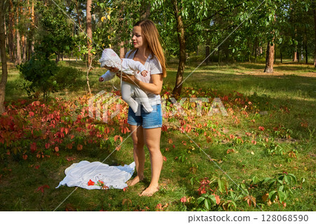 Cute mother with a nice breast newborn baby in a sunny lawn Cute mother with a nice breast newborn baby in a sunny lawn 128068590