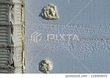 Styrofoam insulation panel with adhesive,brick wall,installation 128068605