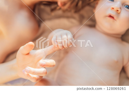 Older and younger baby brothers lying on a soft muslin blanket in warm sunlight, bonding and interacting. Concept of sibling love, early connection, and family warmth 128069261