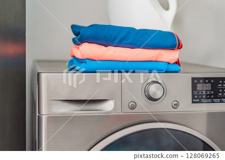Stack of clean sports towels neatly folded on a modern washing machine in a bright laundry room. Concept of fitness hygiene, active lifestyle, and home care routine 128069265