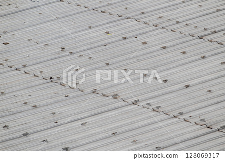 Detailed diagonal view of weathered gray corrugated metal roof surface 128069317
