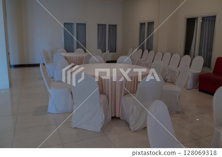 Clean and neat event space with white covered chairs ready for guests 128069318