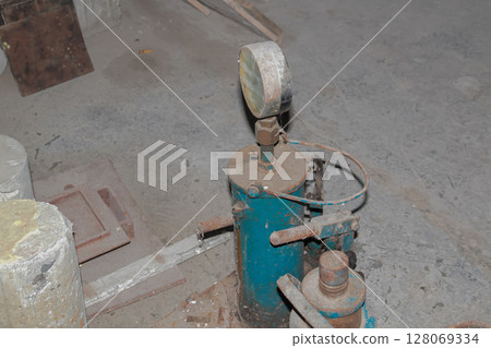 Close-up view of old industrial pressure testing equipment with gauge on concrete floor 128069334