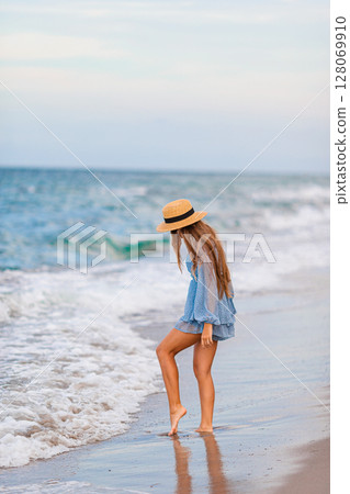 Adorable young girl with beautiful long hair enjoy tropical beach vacation. The girl on the seashore at sunset 128069910