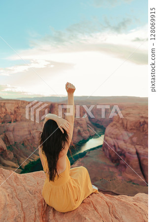 Beautiful woman in yellow dress on the edge of the cliff at Horseshoe Band Canyon in Paje, Arizona. Beautiful nature in USA 128069915