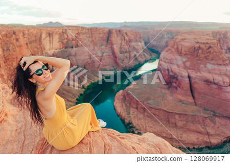 Beautiful woman in yellow dress on the edge of the cliff at Horseshoe Band Canyon in Paje, Arizona. Beautiful nature in USA Beautiful woman in yellow dress on the edge of the cliff at Horseshoe Band Canyon in Paje, Arizona. Beautiful nature in USA 128069917