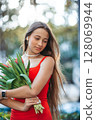 Adorable girl holding bouquet of red tulips in outdoor cafe 128069944
