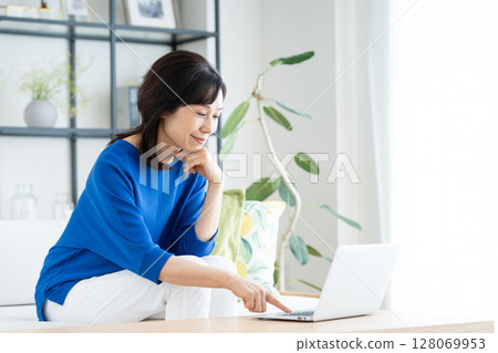 A middle-aged housewife using a computer in the living room 128069953