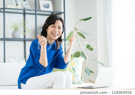 A middle-aged housewife using a computer in the living room 128069956