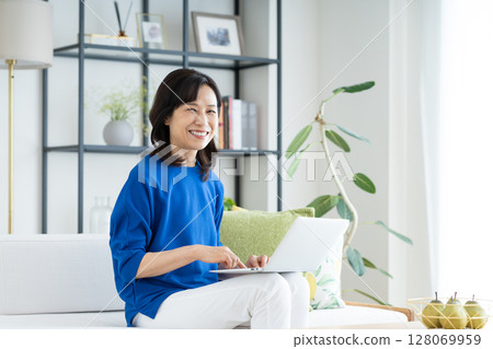 A middle-aged housewife using a computer in the living room 128069959