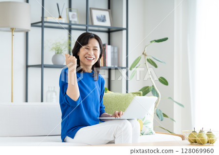 A middle-aged housewife using a computer in the living room 128069960