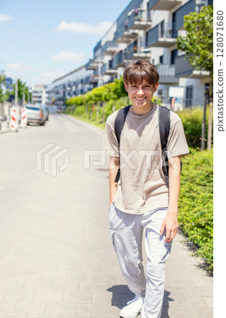 Cheerful cute teenage boy with a backpack walking down the street in sweatpants and a T-shirt 128071680