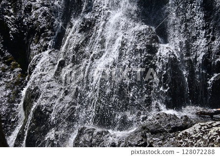 A white stream running through black rocks A white stream running through black rocks 128072288