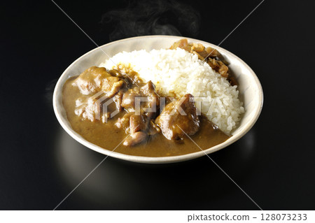 Hot chicken curry with large chunks of chicken photographed against a black background 128073233