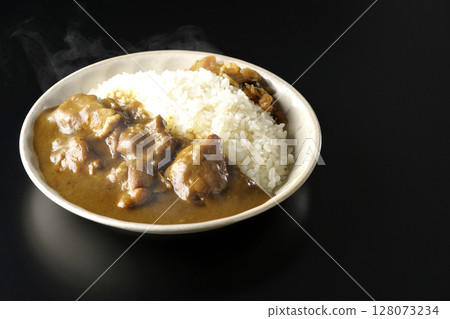 Hot chicken curry with large chunks of chicken photographed against a black background 128073234