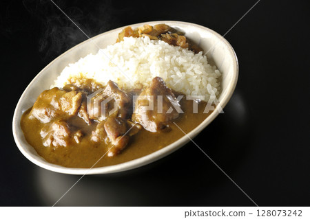 Hot chicken curry with large chunks of chicken photographed against a black background Hot chicken curry with large chunks of chicken photographed against a black background 128073242