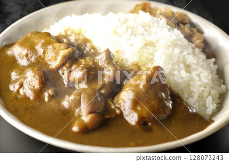 Hot chicken curry with large chunks of chicken photographed against a black background Hot chicken curry with large chunks of chicken photographed against a black background 128073243