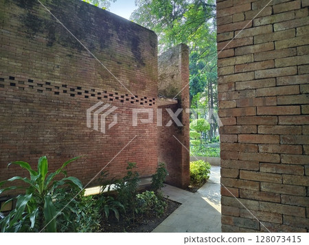 a shady park in summer with green trees and natural red brick buildings-Kediri, Indonesia june 03 2023 128073415