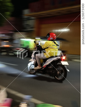 Maxim's online motorcycle taxi with a yellow jacket will pick up passengers in Motion Blurred panning photo, Indonesia - june 26, 2025 Maxim's online motorcycle taxi with a yellow jacket will pick up passengers in Motion Blurred panning photo, Indonesia - june 26, 2025 128073490