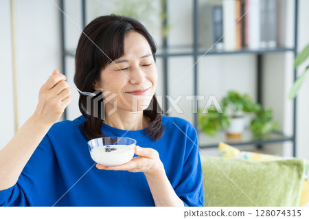 Middle woman eating yogurt Middle woman eating yogurt 128074315
