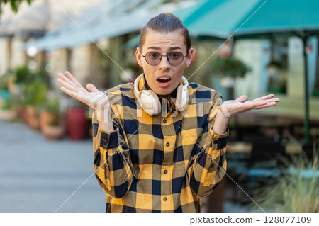 Confused young man tourist having doubts, no idea, being clueless uncertain in urban city street Confused young man tourist having doubts, no idea, being clueless uncertain in urban city street 128077109