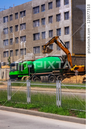 A large green concrete mixer truck is being loaded with fresh concrete A large green concrete mixer truck is being loaded with fresh concrete 128077318