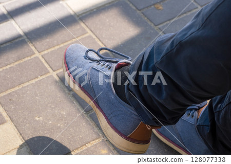 A person wears stylish blue shoes with a distinct brown sole 128077338