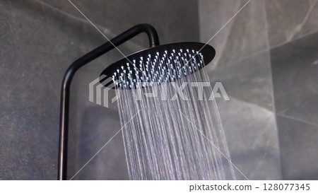 A detailed close up of a shower head with water flowing out of it 128077345