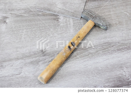 A sturdy hammer featuring a wooden handle rests on a wooden table A sturdy hammer featuring a wooden handle rests on a wooden table 128077374