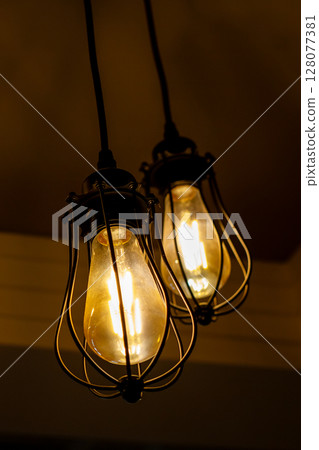 Three light bulbs are hanging down from the ceiling in a dark room Three light bulbs are hanging down from the ceiling in a dark room 128077381